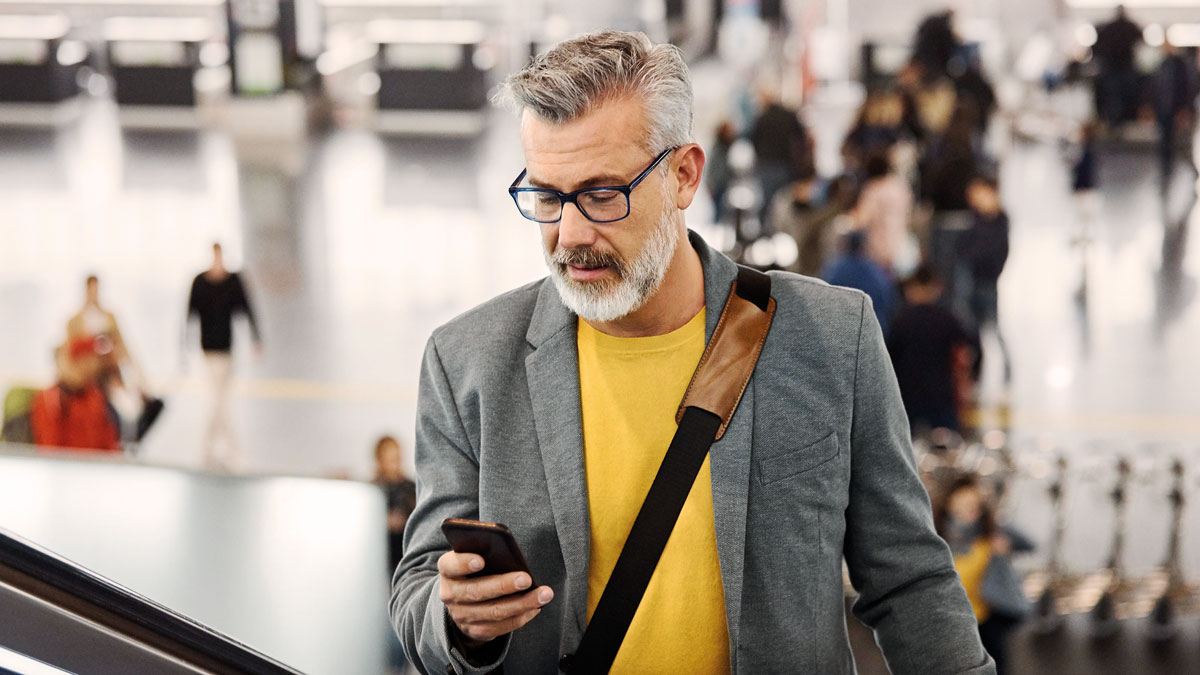 A man on a escalator holding a smart-phone in a airport